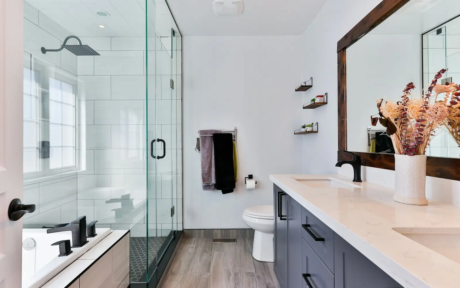 Modern bathroom with glass shower, white tile and wood vanity