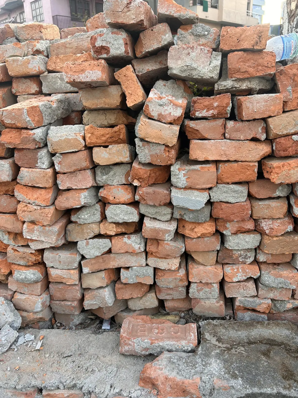 Stack of weathered red bricks with traces of old gray mortar