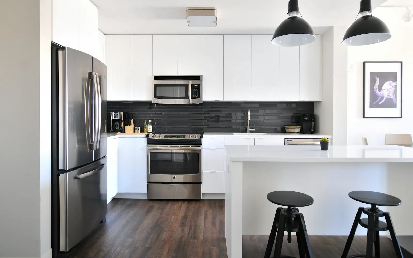 Bright white kitchen with painted cabinets, pendant lights and stools