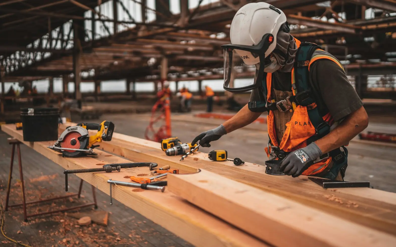 Person in safety gear working with tools on a wood workbench